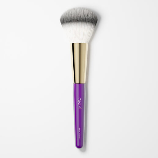 Large powder brush with dense white bristles, a purple handle, and gold accents on a plain white background.