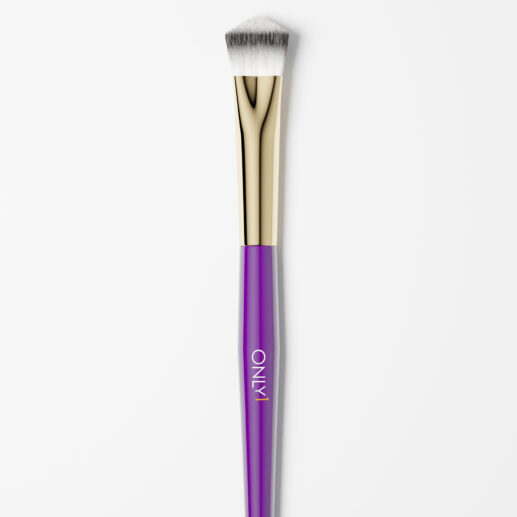 Small concealing brush with a purple handle, gold accents, and white bristles on a plain white background.