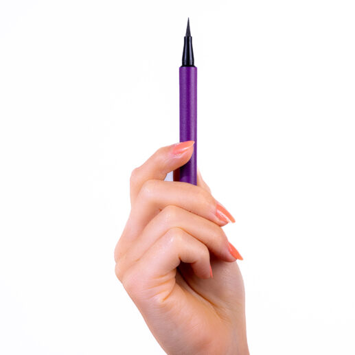 Hand holding a purple liquid eyeliner pen with a fine black tip against a plain white background.